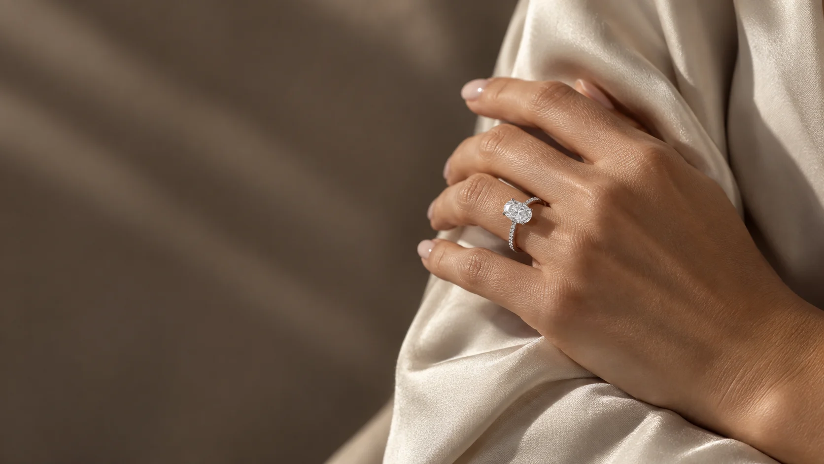AI-generated styling illustration of an oval diamond ring on a hand resting against ivory silk