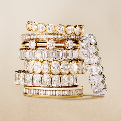 A stack of diamond eternity rings in round, oval and emerald cuts
