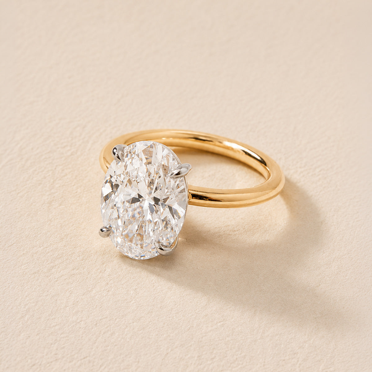 A close-up of an oval diamond solitaire in a fine gold setting