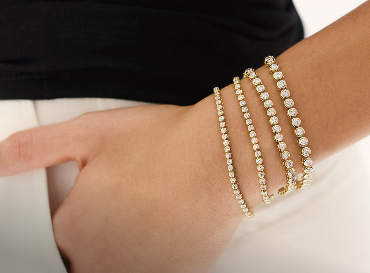 A close-up of bezel-set diamond tennis bracelets worn together